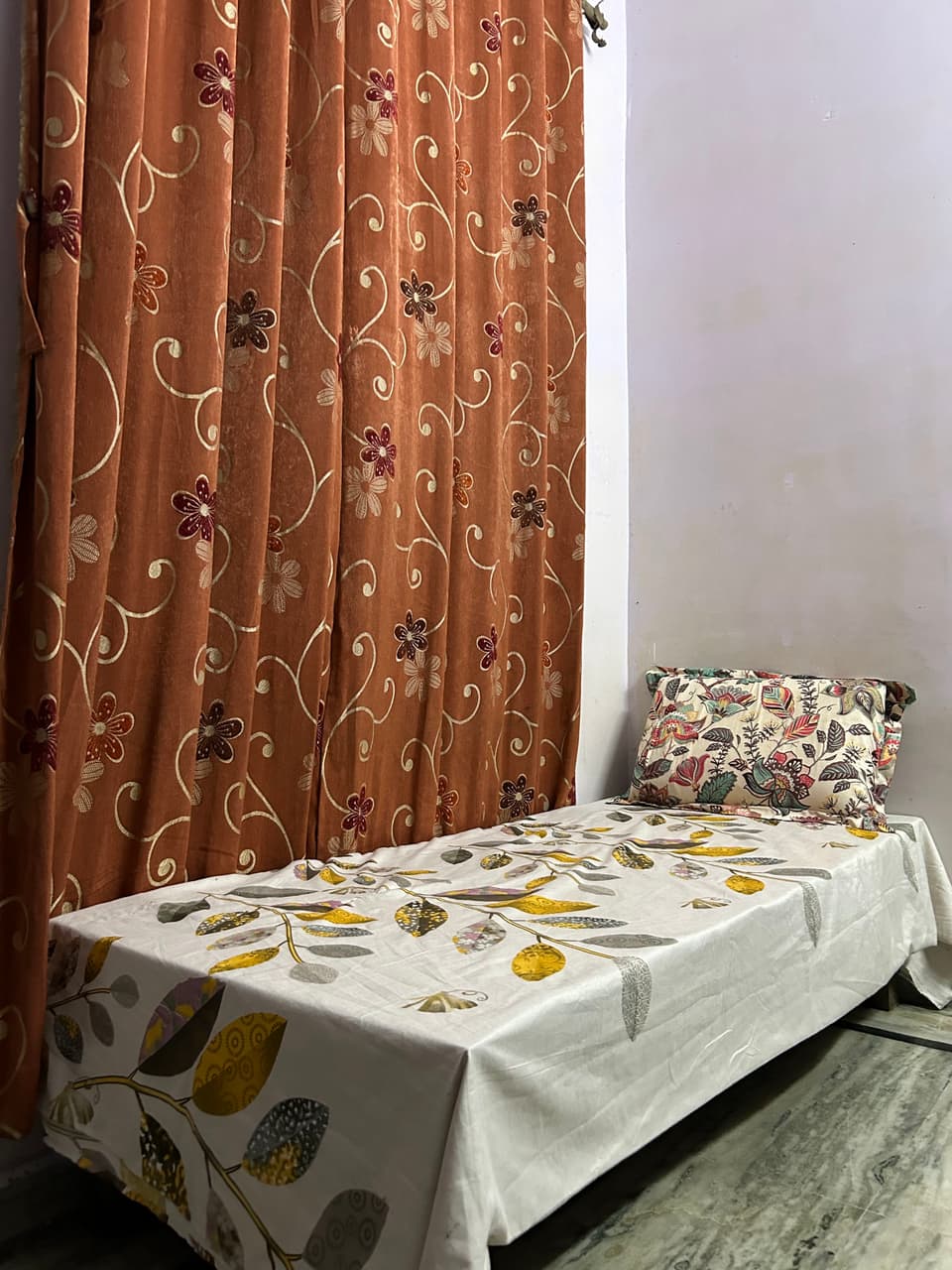 Single bed beside the window curtain.