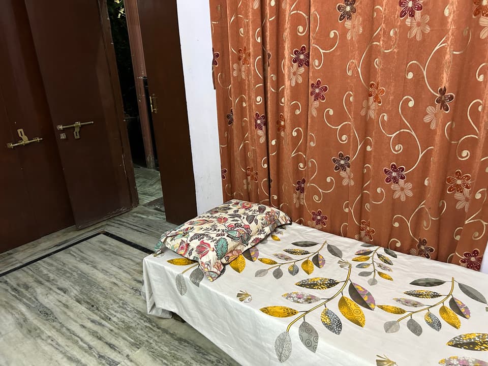 Single bed beside the entrance and window curtain.
