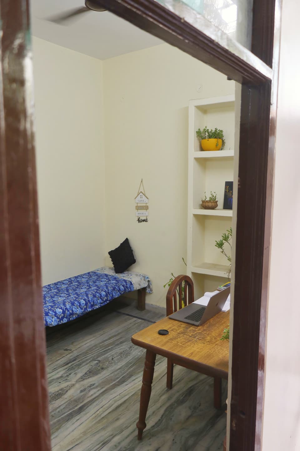 Single bed and study desk viewed from the room entrance.