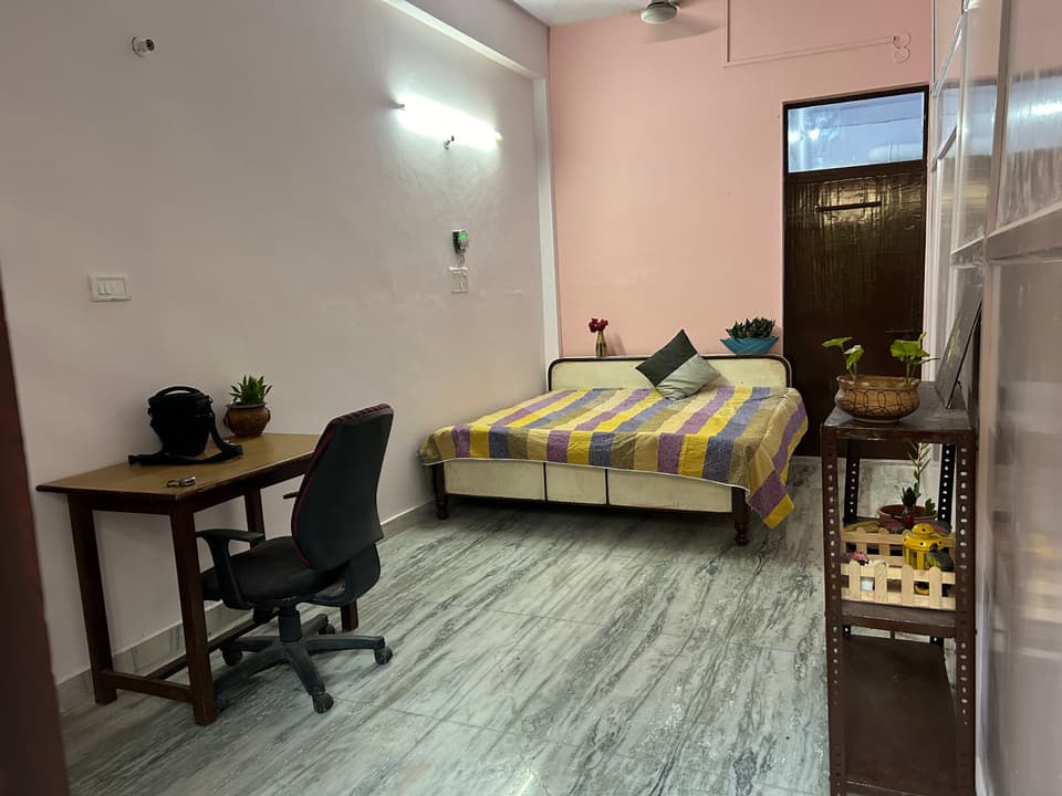 Garden-view studio room with bed, desk, and open floor area.