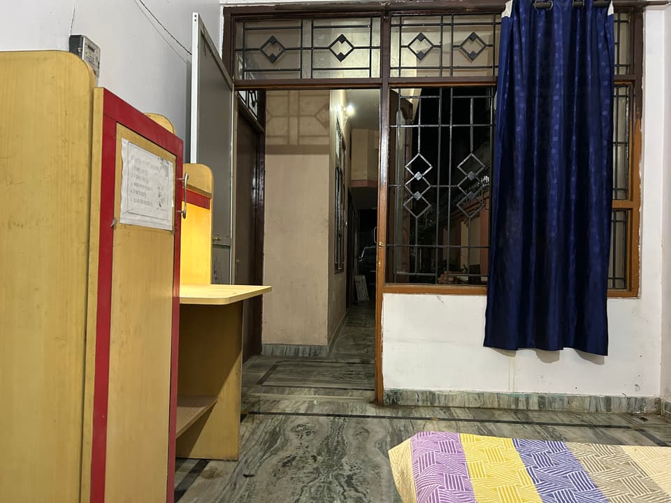 Study desk, storage unit, and large window viewed from the bed.